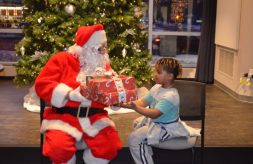 Santa gives a stack of gifts from DSCC staff to an eager Club Compass student.