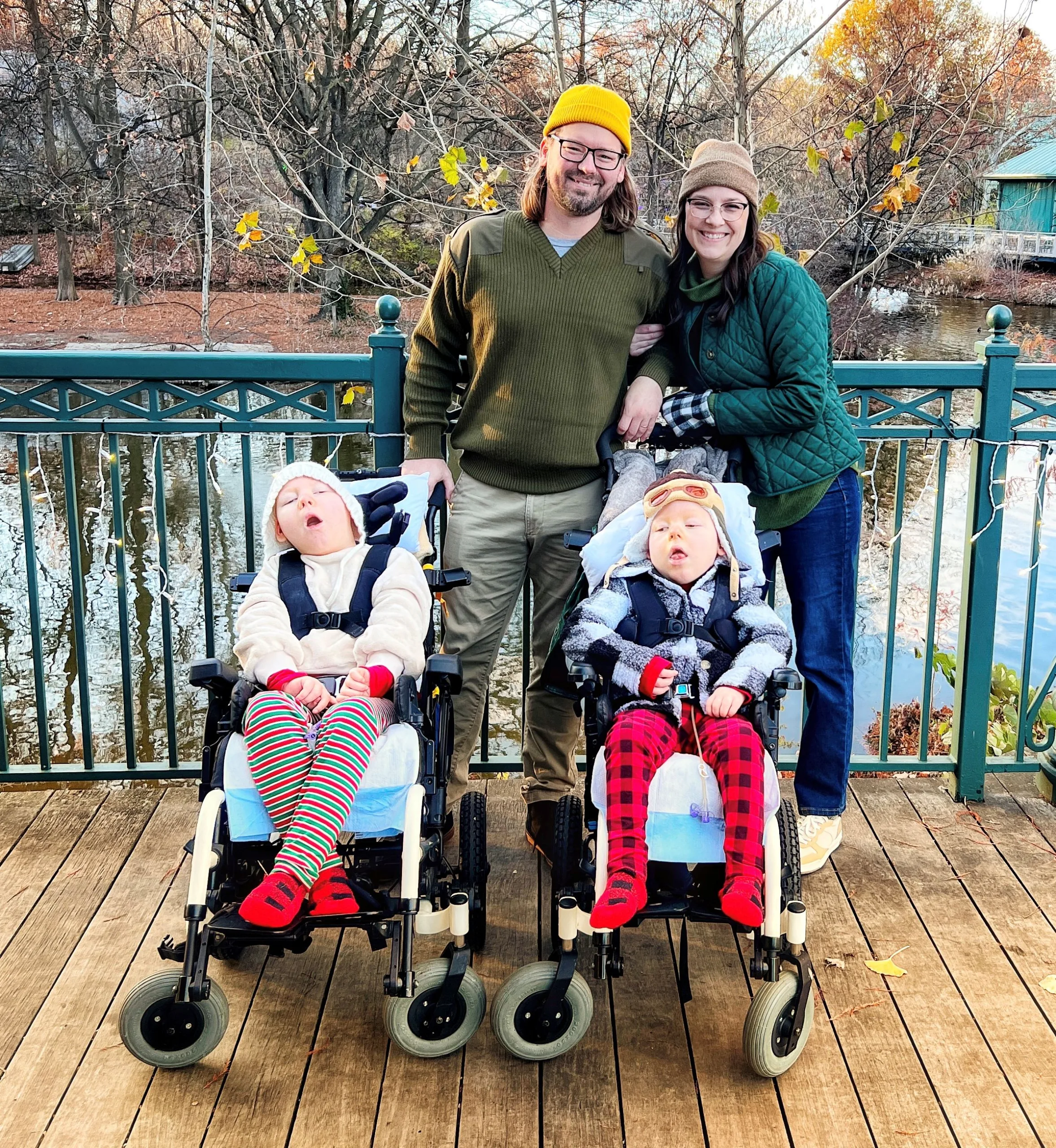 Erica Stearns and her husband stand arm-in-arm between their children Margot and Caratacus Stearns who are in medical wheelchairs while the family enjoys time outdoors