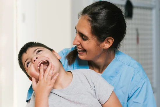 A nurse holds a laughing boy with cerebral palsy